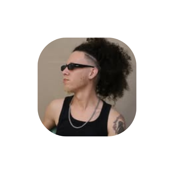 Artista Jailson Miguel de perfil, cor de pele branca branco, usa oculos escuro preto, usa camiseta regata preta e corrente no pescoço e tem uma tatooagem no ombro